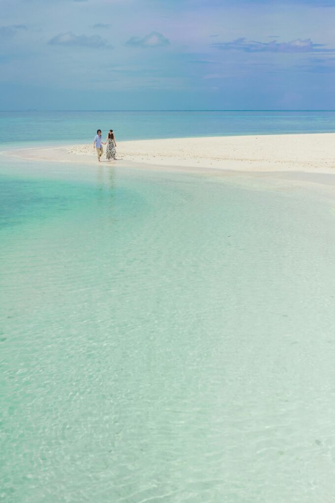 A couple enjoys a romantic walk on a serene white sand beach in the Maldives.