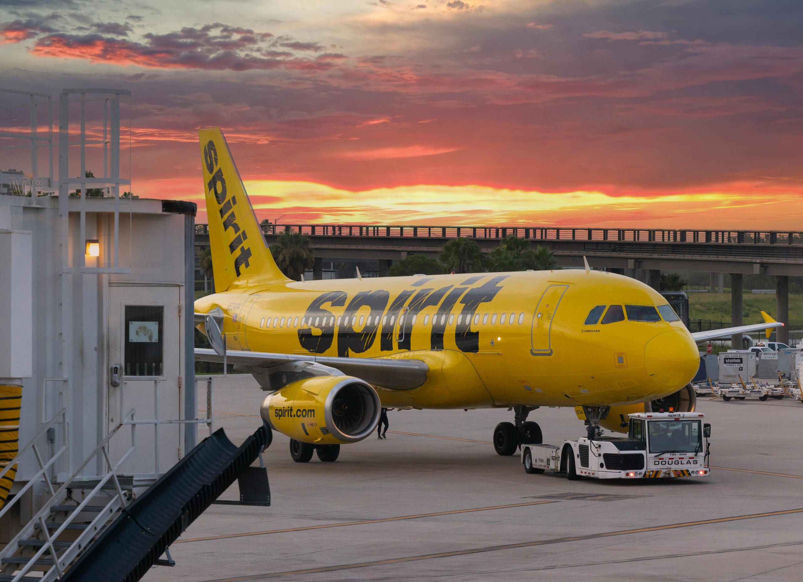 A Spirit Airlines plane at Manchester Airport during a stunning sunset sky, showcasing travel ambiance.