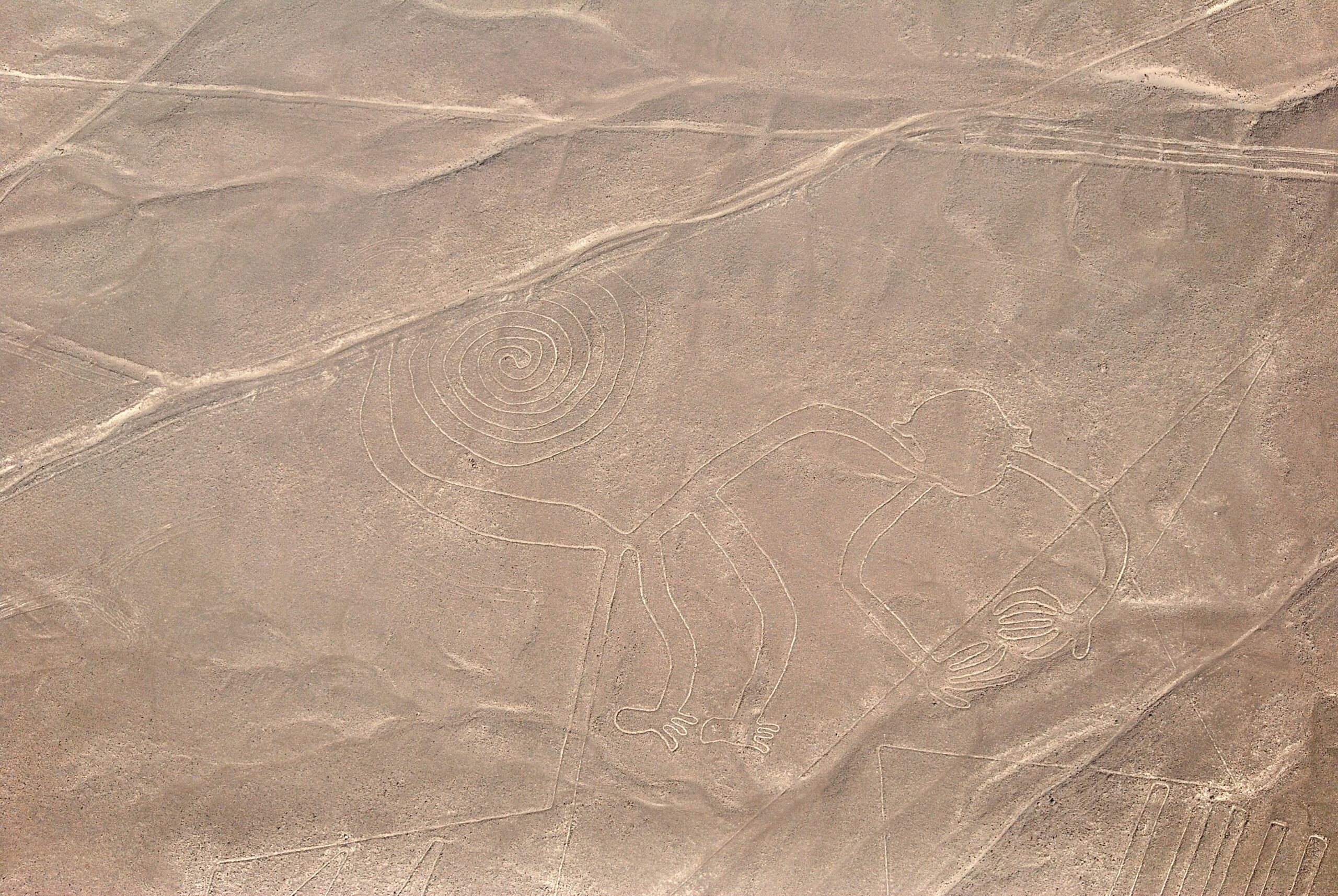 A stunning aerial capture of the iconic Nazca Lines, including the spiral and monkey figures, in Peru's desert landscape.