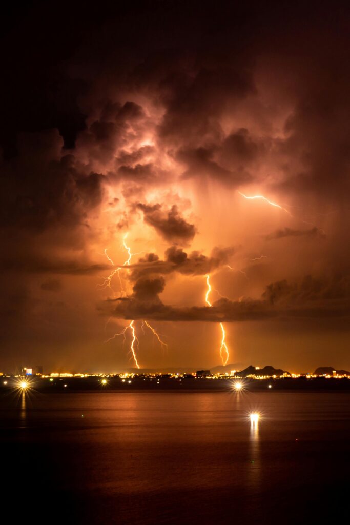 A stunning capture of a thunderstorm with lightning illuminating the coastal skyline at night.