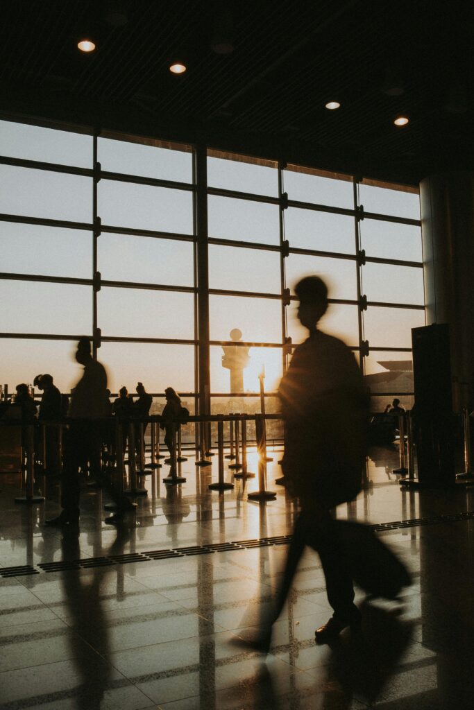 Passengers silhouetted against sunrise in an airport terminal, capturing the essence of travel.