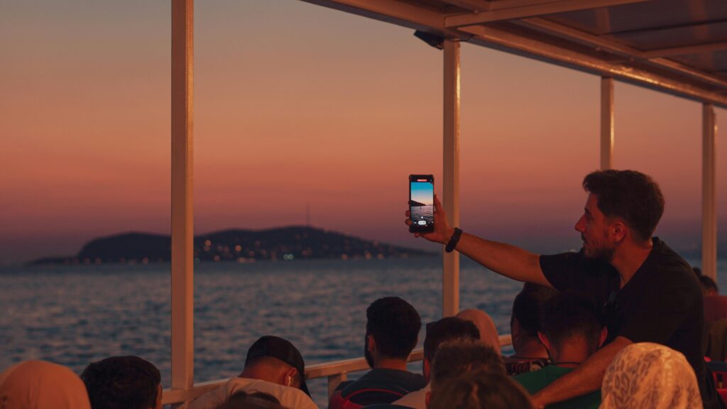 A man taking a picture of the sunset on a boat