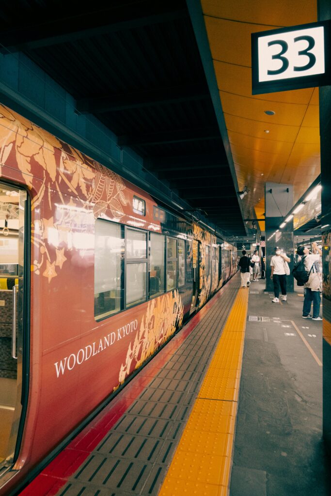 Vibrant scene at Kyoto station featuring the Woodland Kyoto train on platform 33.