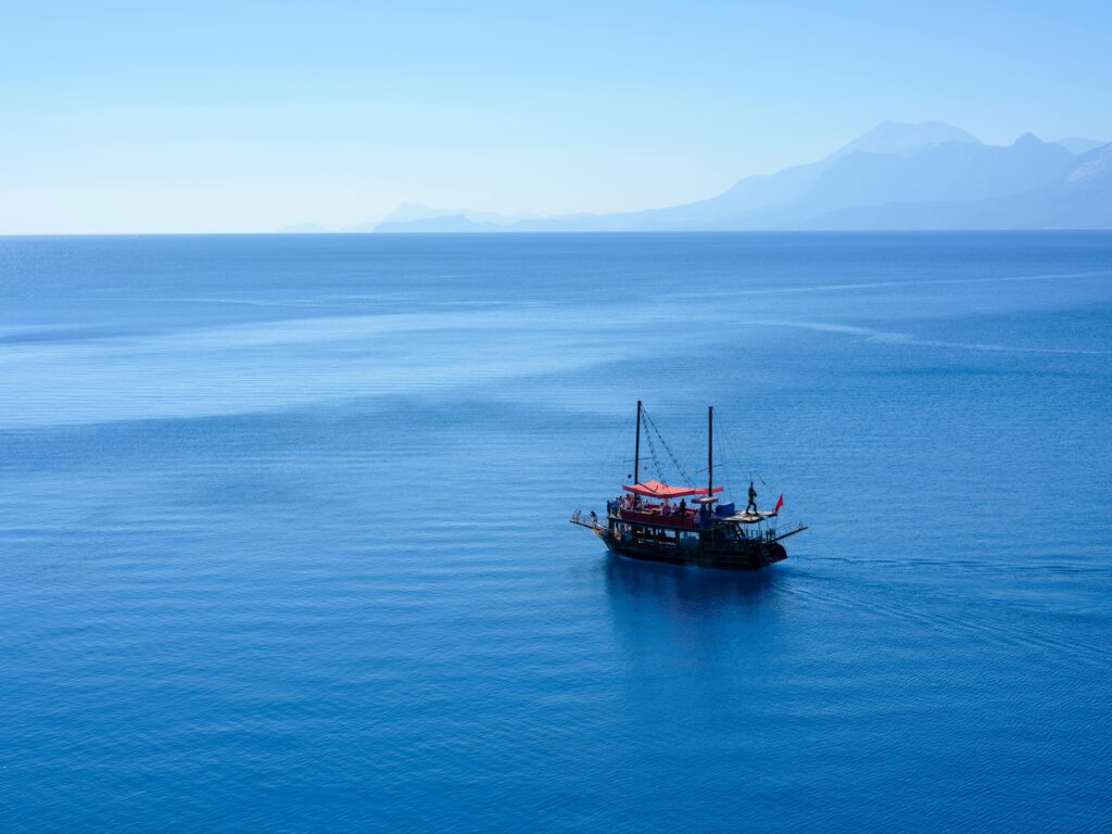 A picturesque aerial view of a lone sailboat cruising on a tranquil blue sea under clear skies.