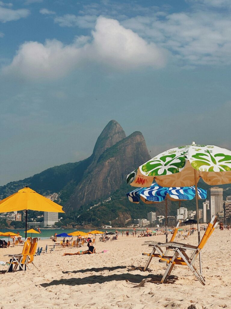 Enjoy a sunny day at Ipanema Beach, Brazil with iconic mountain views and colorful umbrellas.