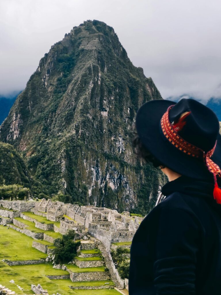 A person gazes at the historic Inca site of Machu Picchu in Peru, surrounded by stunning mountain peaks.