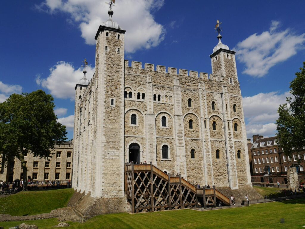 The iconic White Tower of London with its historic architecture and bright blue sky backdrop.