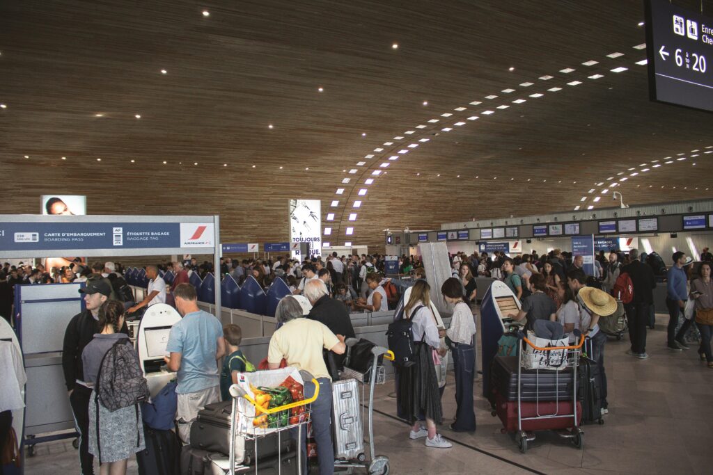 Crowded airport terminal with travellers in line. Indoor setting with modern architecture.