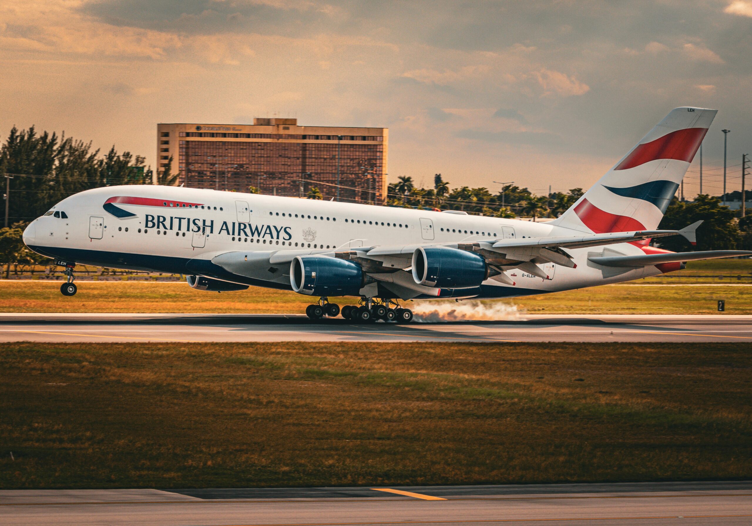 A British Airways Airbus A380 lands on a runway during sunset, showcasing aviation travel.