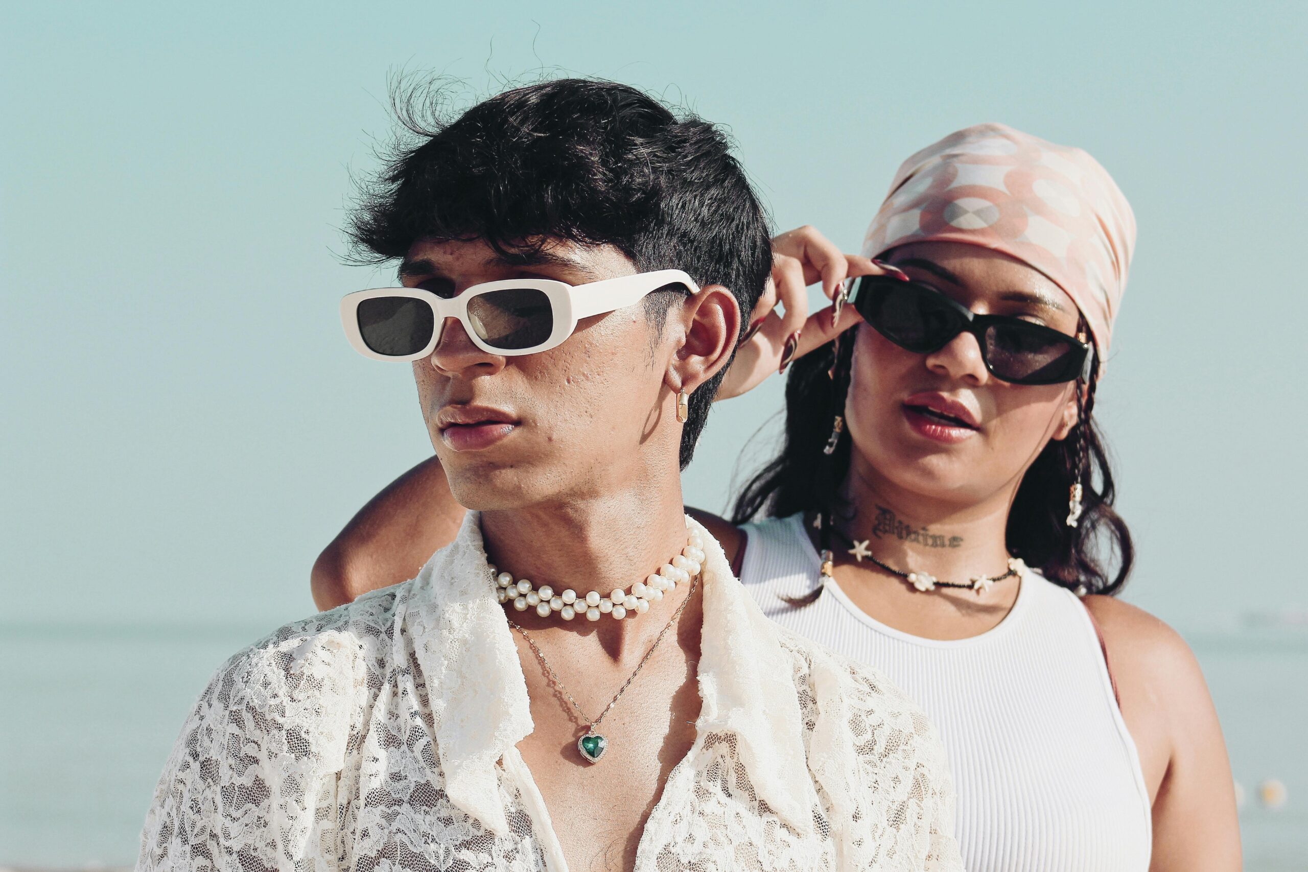 Fashionable young adults wearing sunglasses and casual beachwear on a sunny day at the beach.