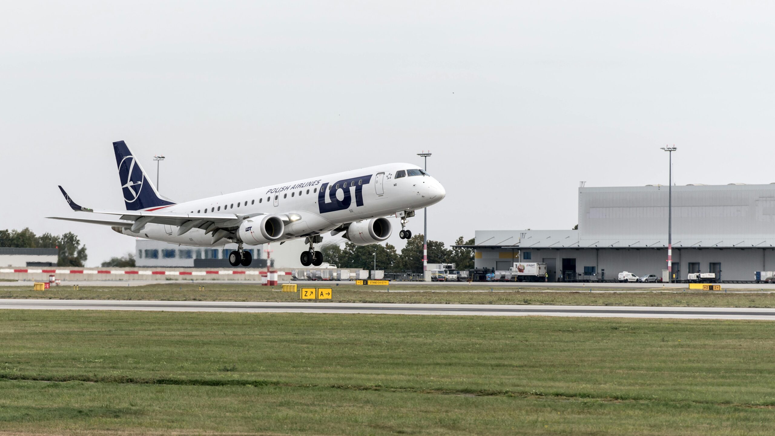 LOT Polish Airlines aircraft takes off from the airport runway during the day.