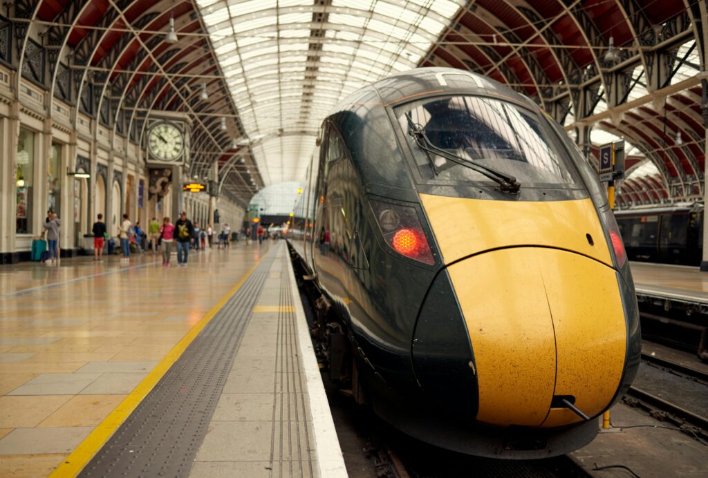 A sleek modern train at an urban railway station with commuters on the platform.