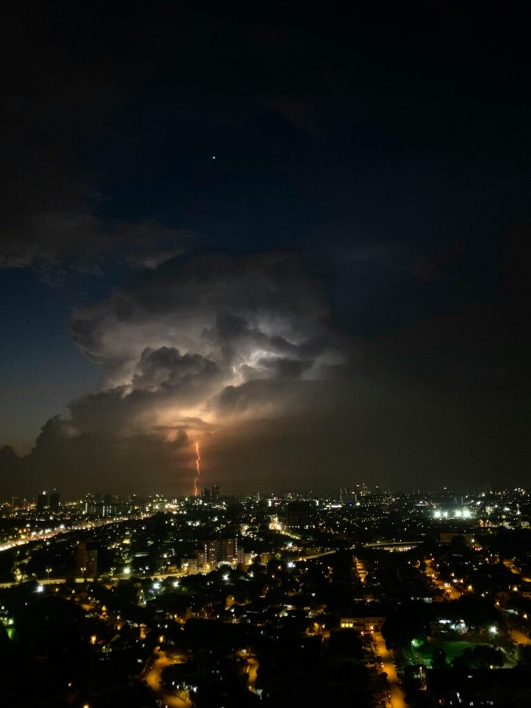 City With High Rise Buildings Under Dark Clouds during Night Time