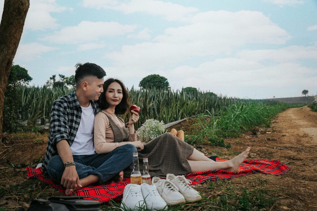 Couple enjoying a romantic picnic outdoors in the scenic fields of Tam Điệp, Vietnam.