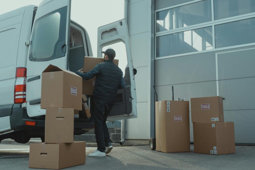 Man in Blue Jacket and Blue Denim Jeans Sitting on Brown Cardboard Box