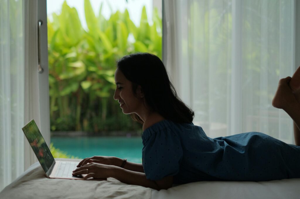 Asian woman working on a laptop indoors in Bali, enjoying a relaxed digital nomad lifestyle.