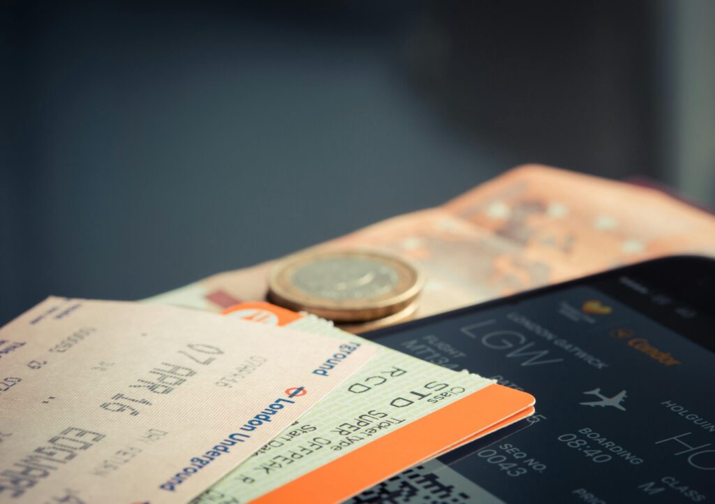 Airline ticket with euro coins and smartphone displaying flight details.