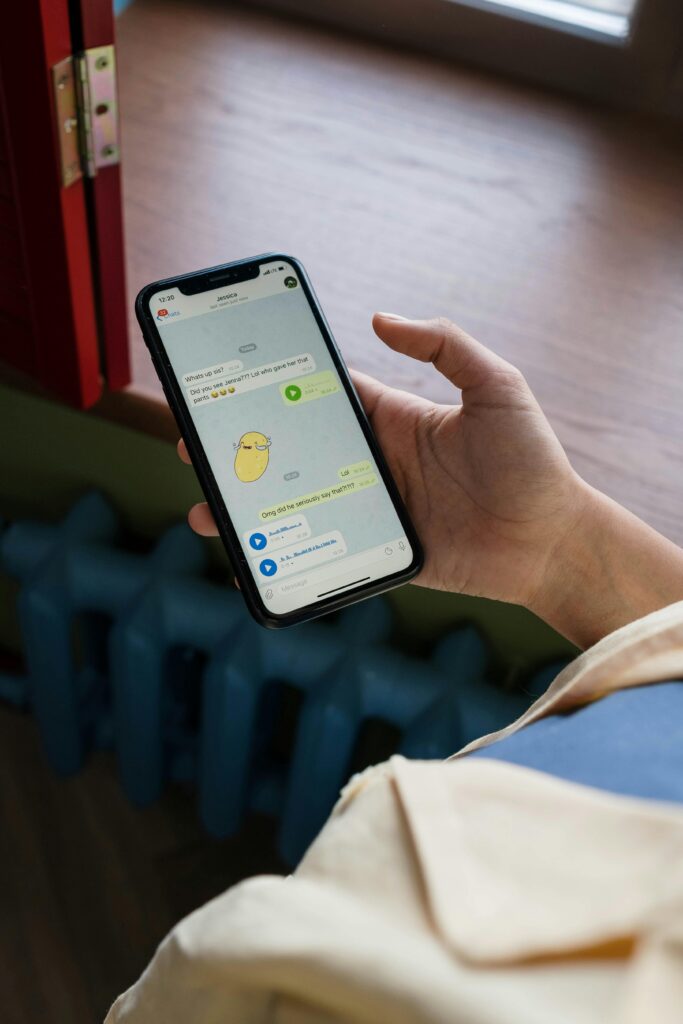 A person holding a smartphone with messaging app displayed, indoors.