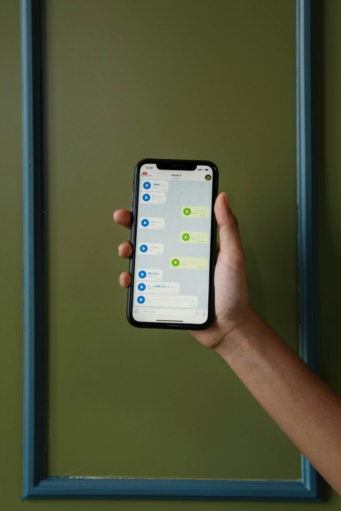 Close-up of a hand holding a smartphone displaying a messaging app.