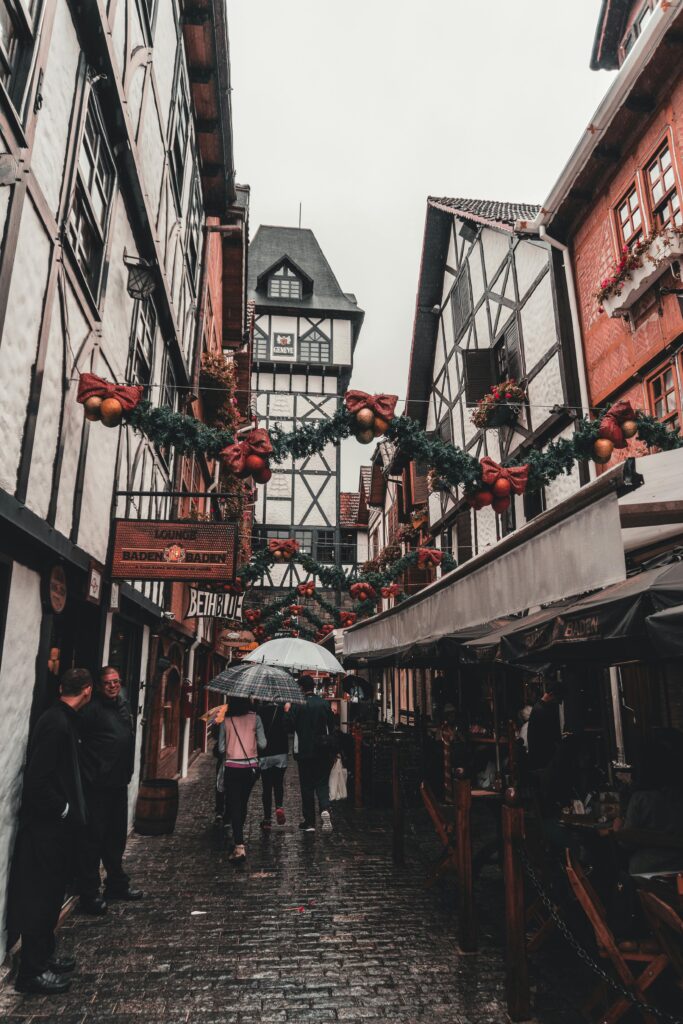 Charming street adorned with Christmas decorations and people walking with umbrellas.