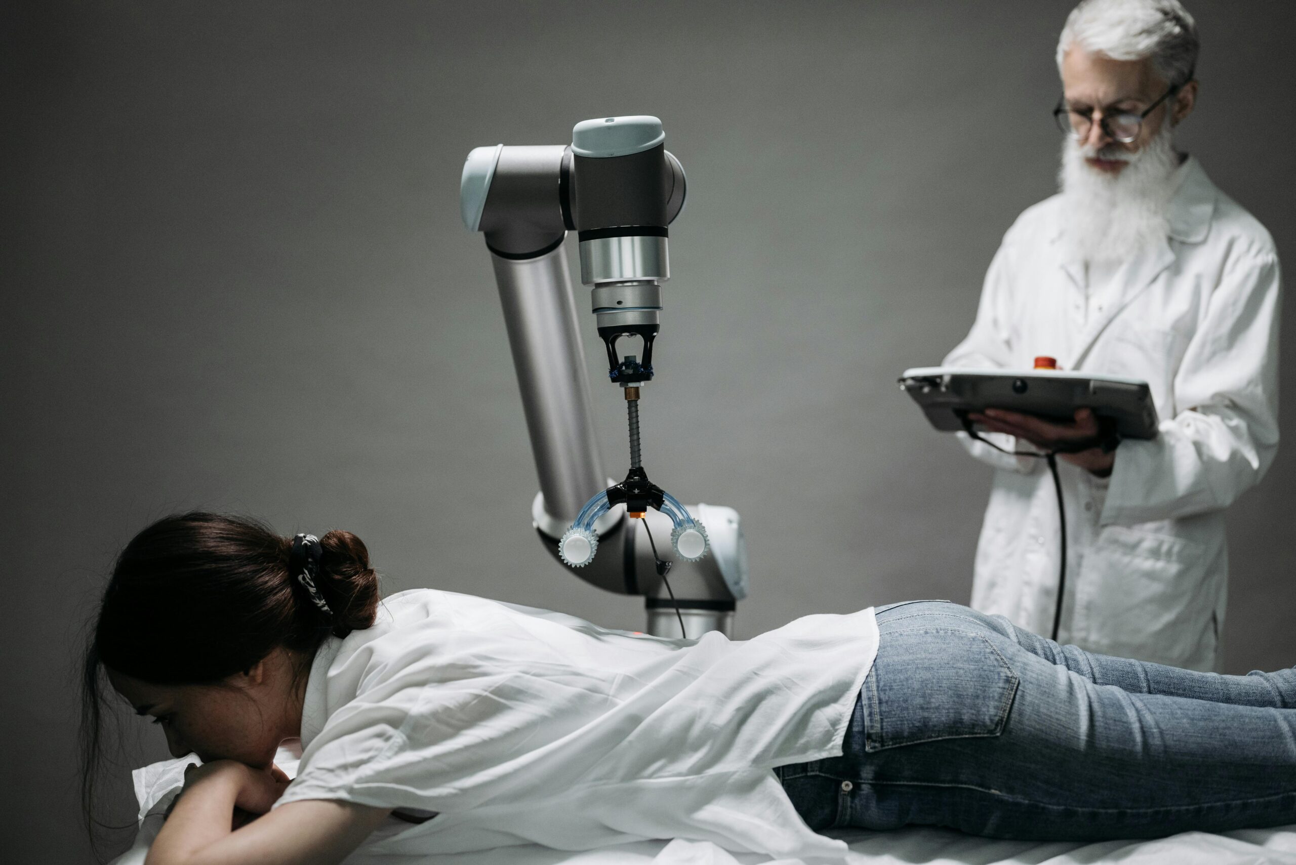 A woman receives a robotic massage as a scientist monitors, showcasing modern technology.