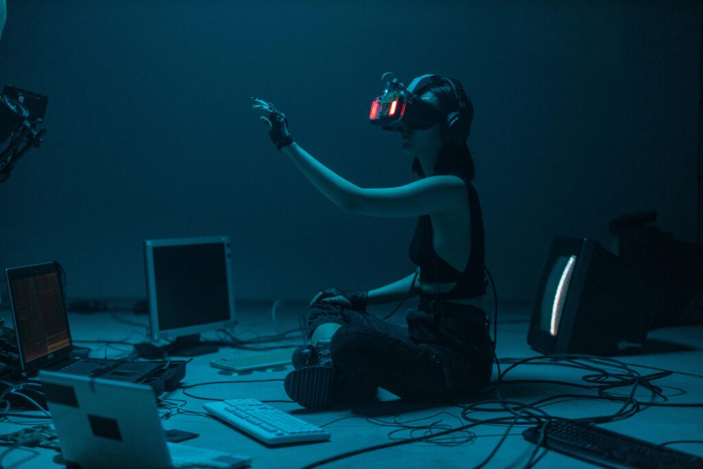 Woman immersed in virtual reality, surrounded by tech, in a dimly lit room.