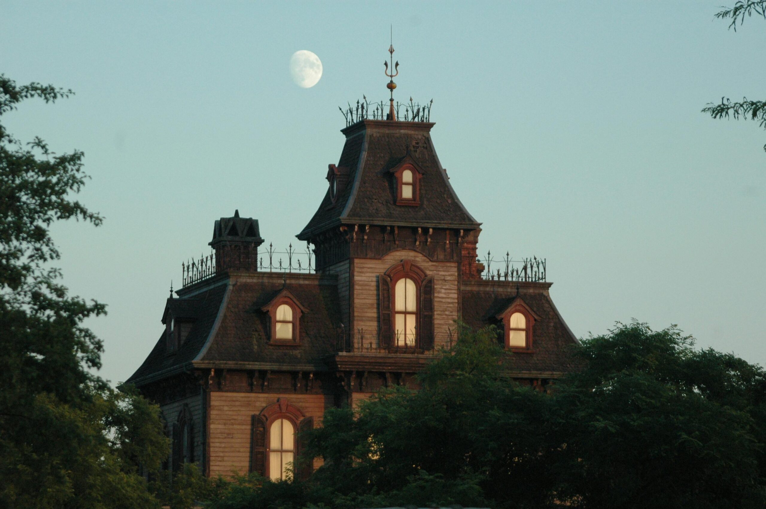 A captivating image of a Victorian mansion under a twilight sky with a visible moon.