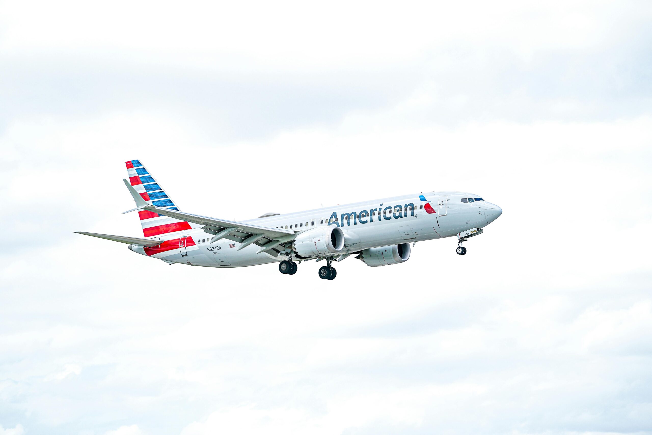 An American Airlines aircraft flying against a bright, cloudy sky, showcasing aviation excellence.