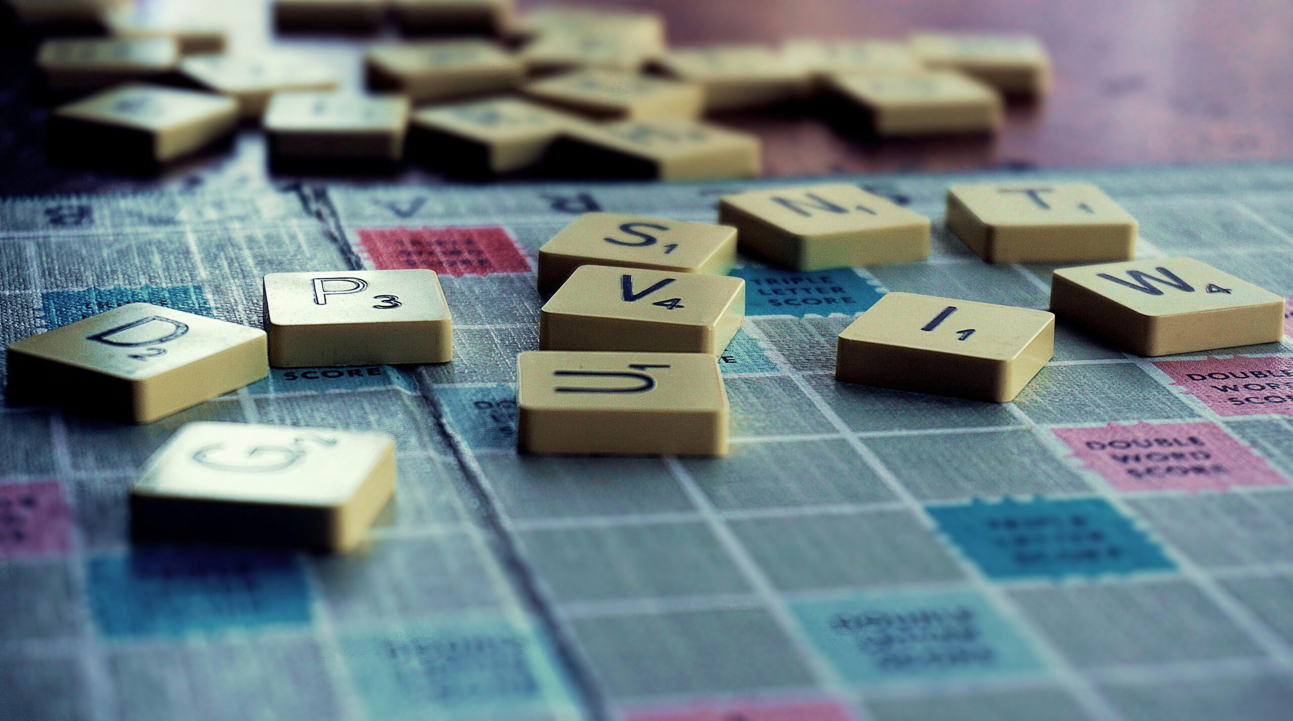 Close-up of Scrabble tiles scattered on the board, capturing leisure and word play.