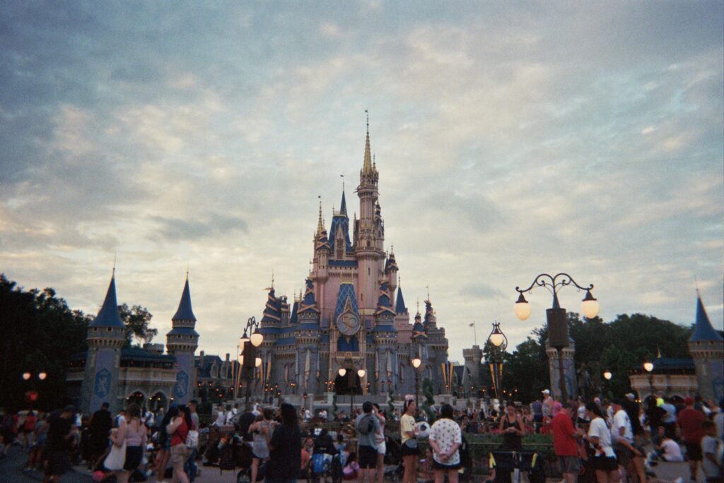 Tourists gather around Cinderella's Castle at Walt Disney World during sunset, capturing a magical moment.