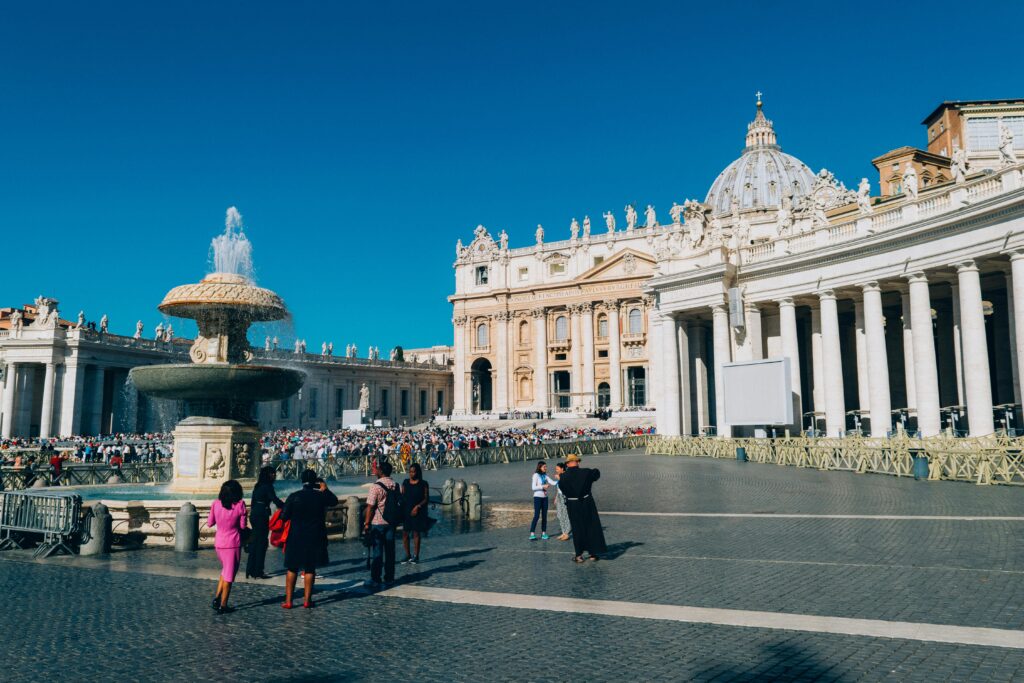 St. Peter's Basilica and fountain in St. Peter's Square, Vatican City, showcasing iconic architecture and tourists.