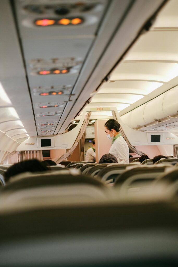 Flight attendant serves passengers in an airplane's cabin interior, focusing on customer service during air travel.