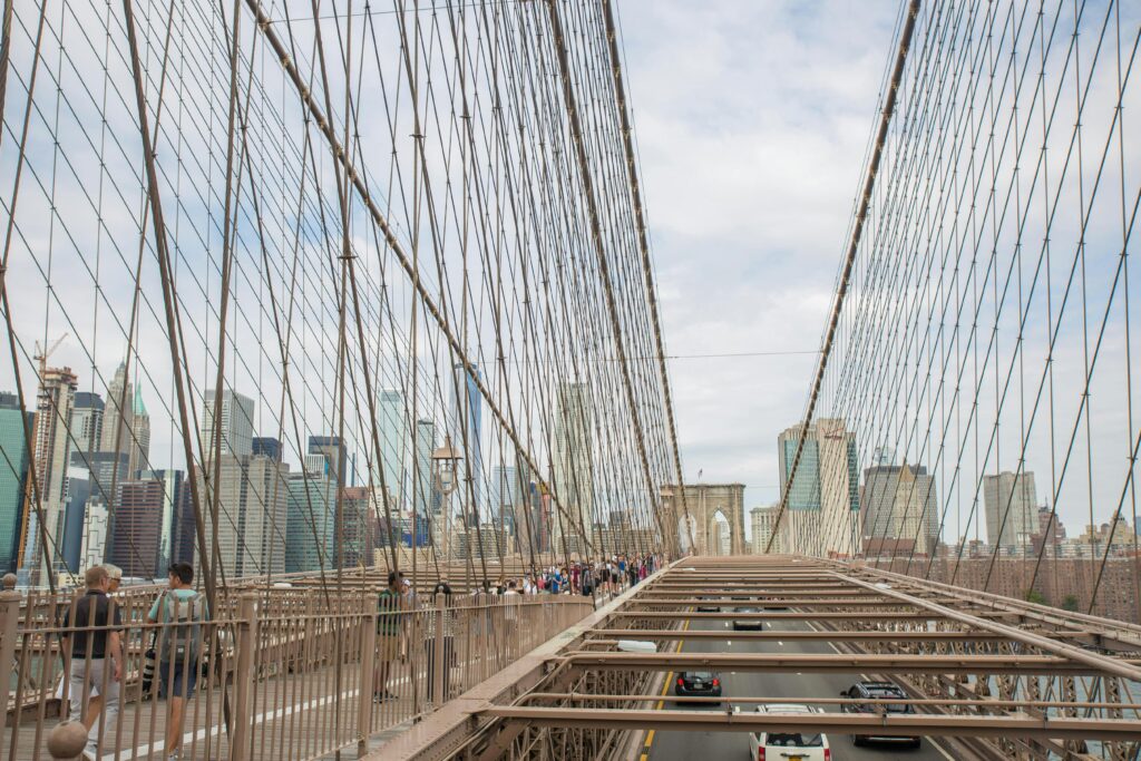 Brooklyn Bridge with people walking, capturing New York skyline under daylight.