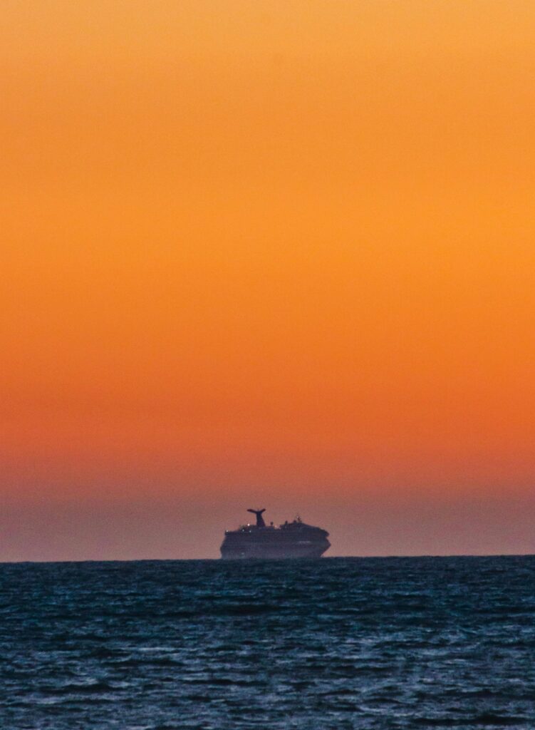 Silhouette of Ship Sailing in Sea on Horizon on Sunset