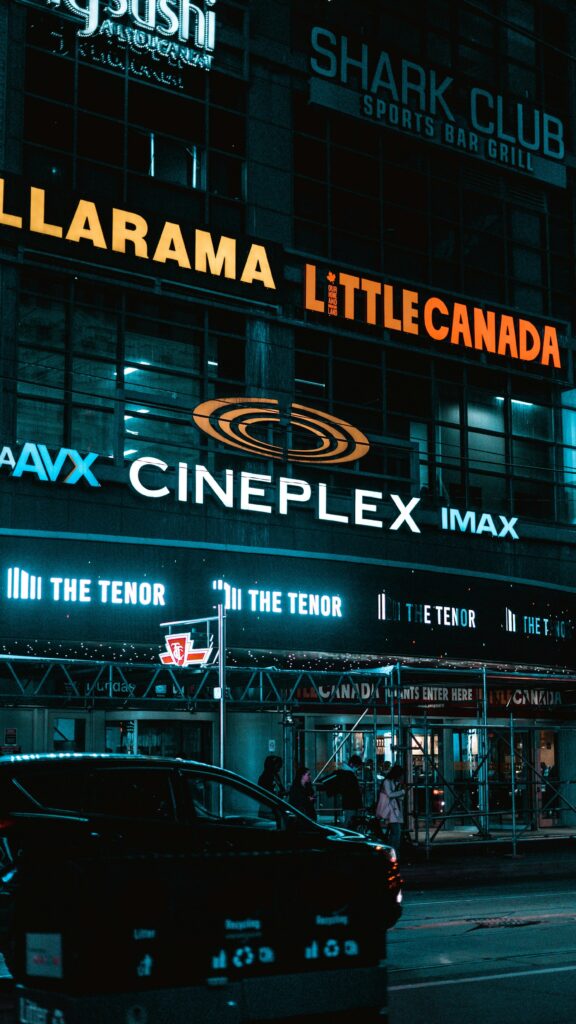 Toronto cityscape featuring Cineplex and neon signs at night with urban atmosphere.