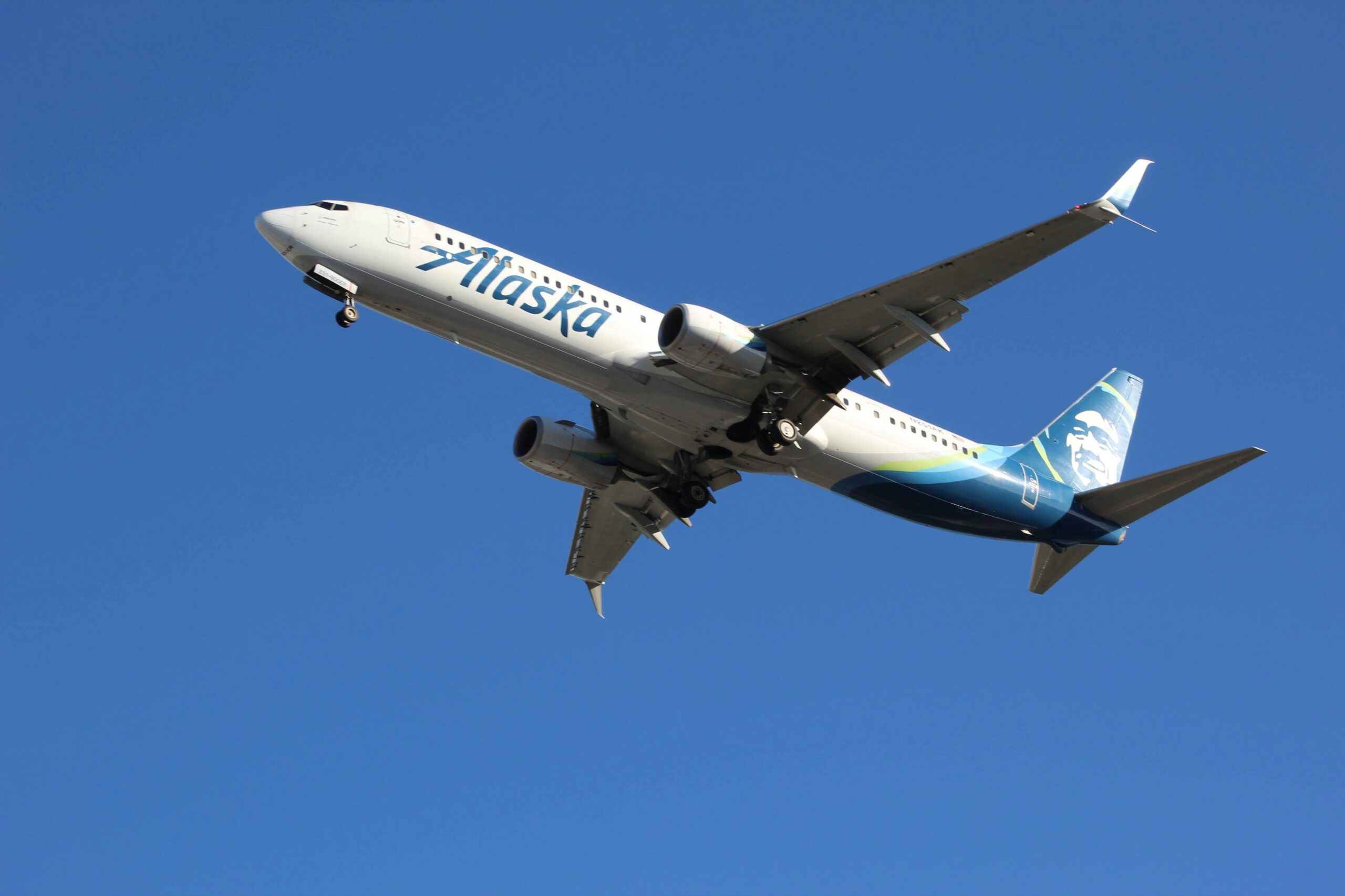 Alaska Airlines jet taking off against a clear blue sky, showcasing modern aviation.