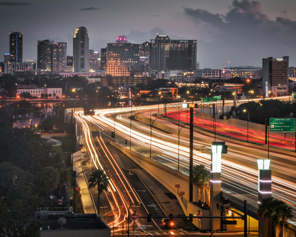 Stunning aerial view of Orlando skyline at dusk, showcasing vibrant light trails and bustling city life.