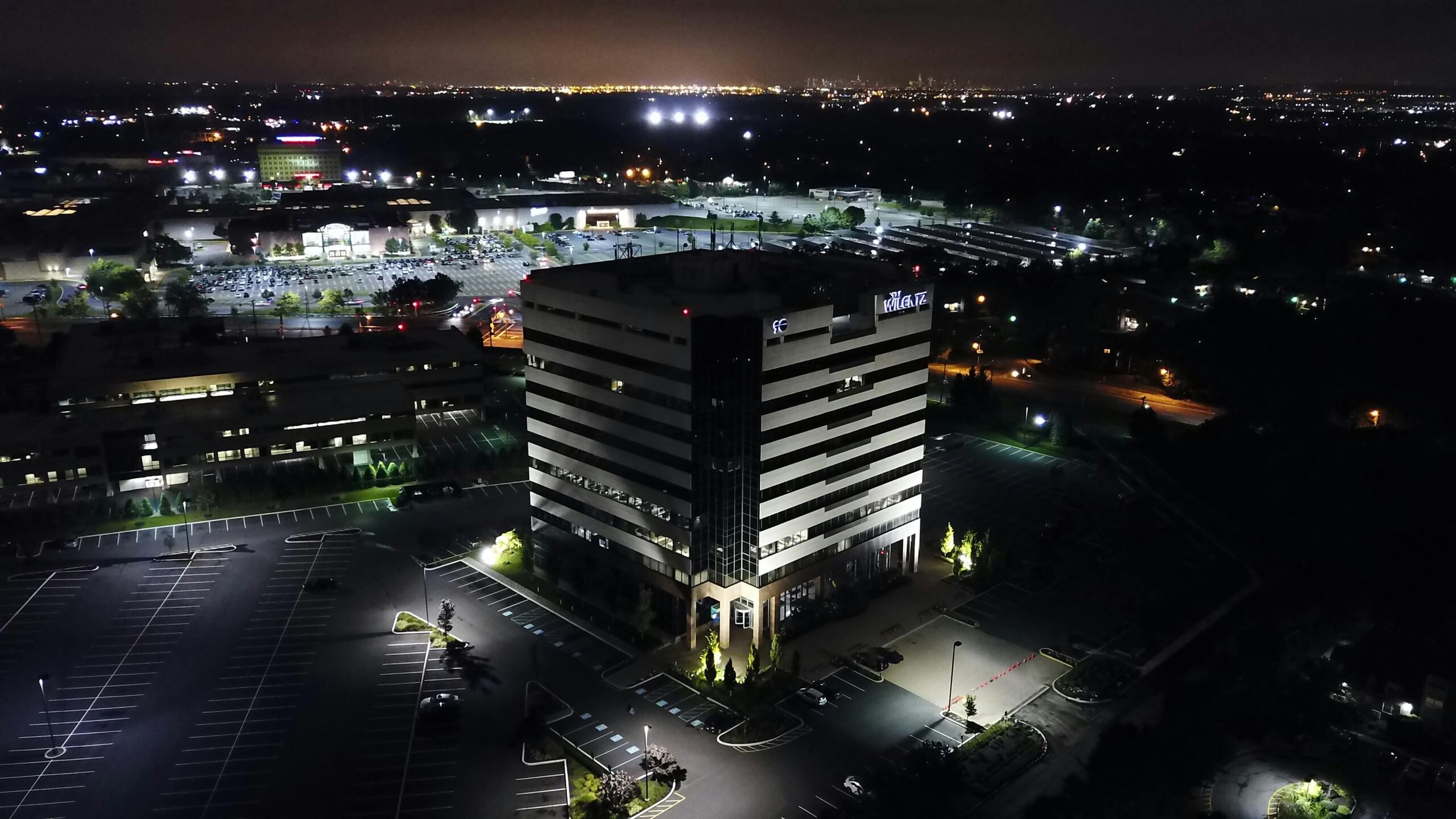 Aerial view of illuminated office building and parking lot at night in Woodbridge Township, NJ.