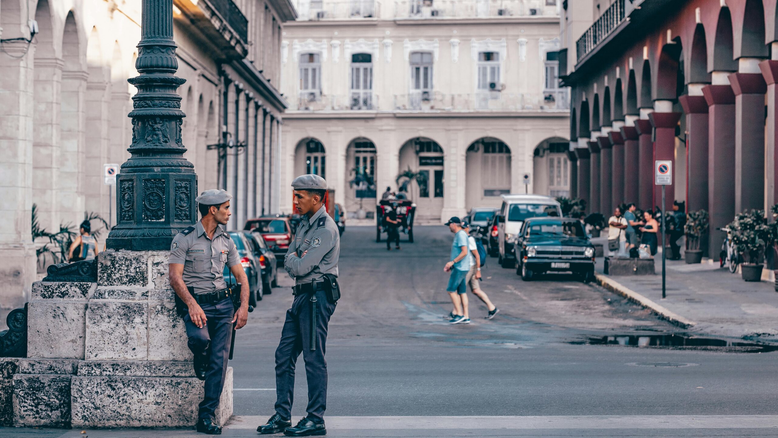 Police officers conversing in a scenic Havana street, showcasing historic architecture.