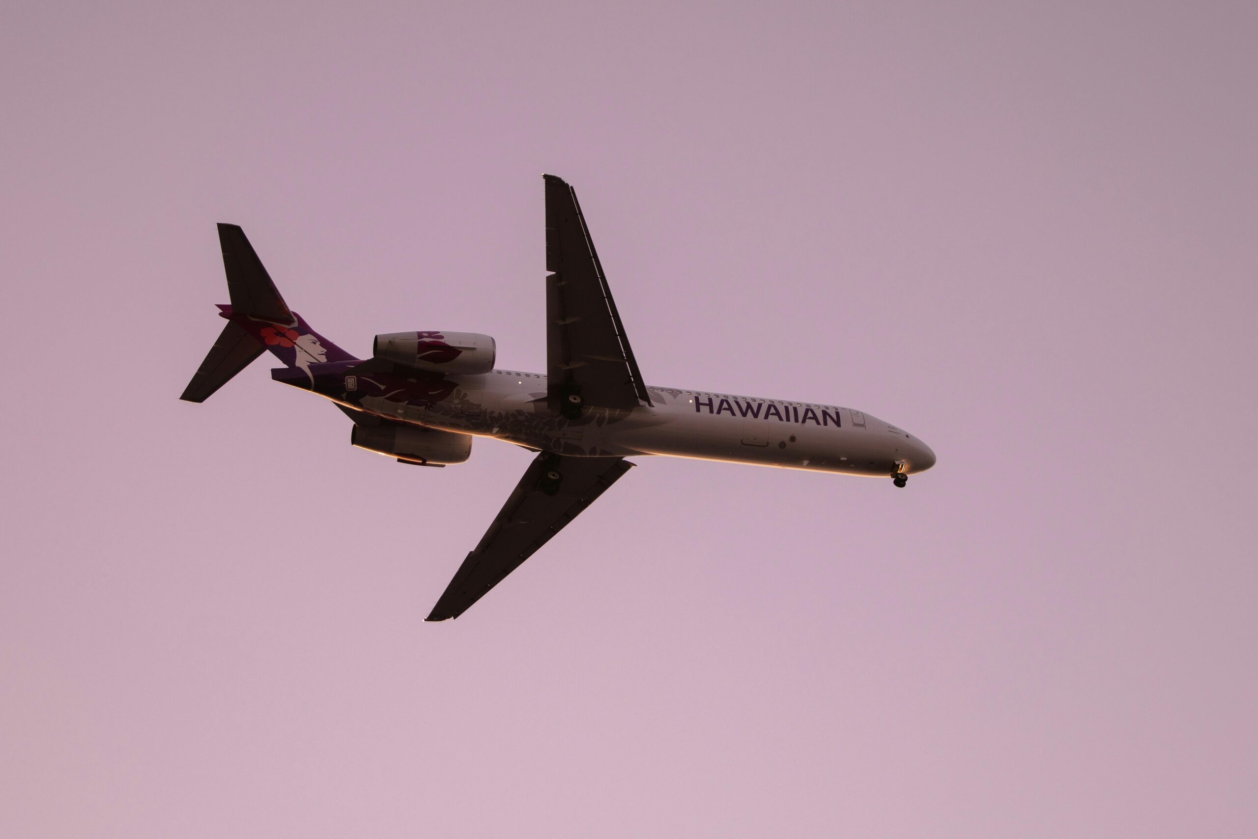 Hawaiian Airlines jet soaring through a clear sky during twilight, Kailua-Kona, Hawaii.