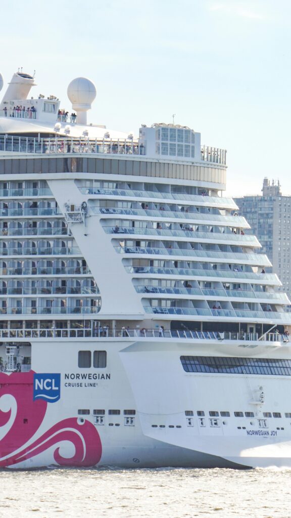 A Norwegian cruise ship sails along the New York City skyline, offering a luxurious travel experience.