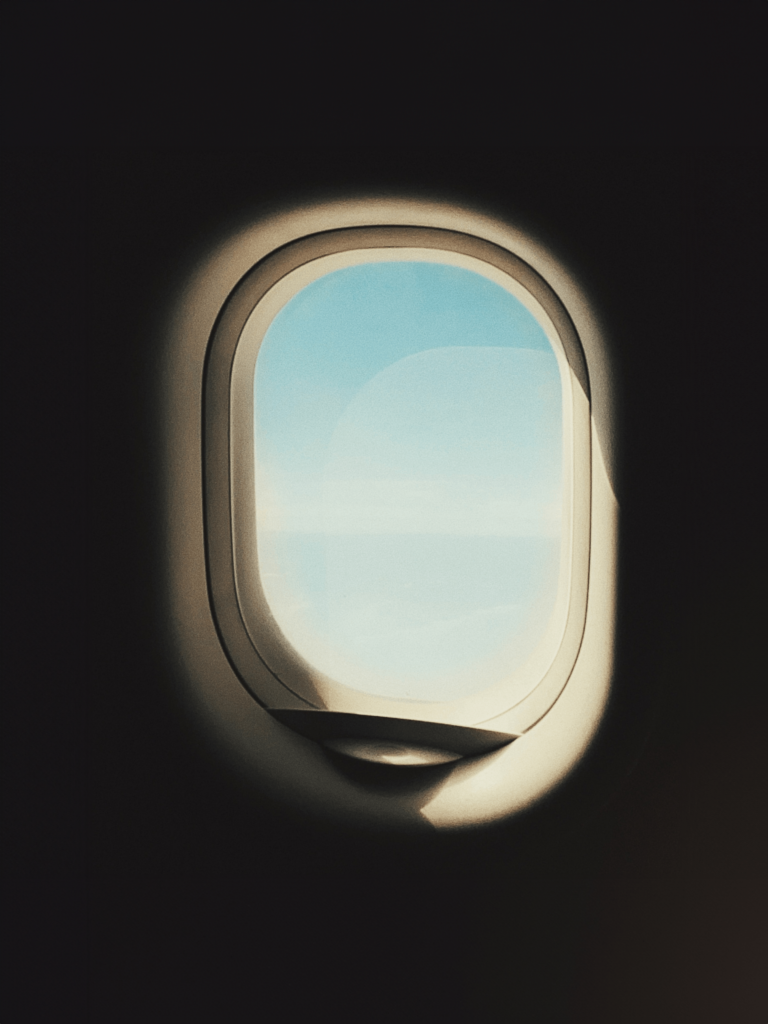 View of the sky from an airplane window with soft lighting and a sense of travel.