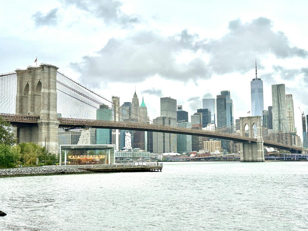 The Brooklyn Bridge spans over the East River, with New York City skyline in the background.