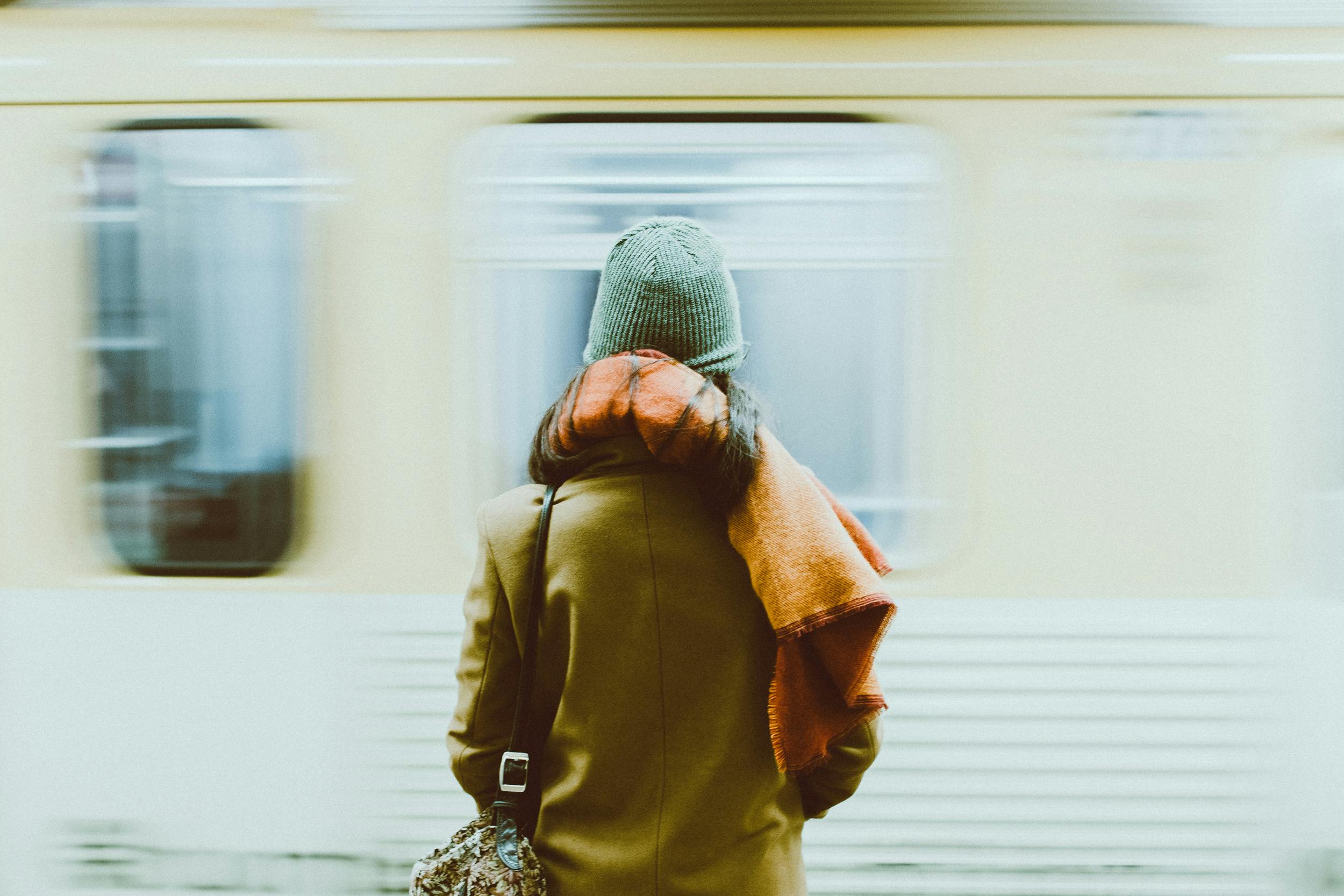 A woman in winter attire waits for a train at a New York subway station.