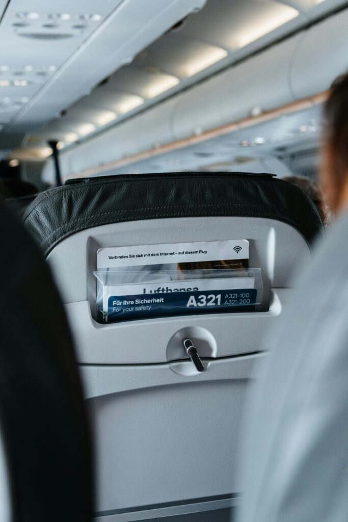 View of a Lufthansa seat pocket with safety instructions inside an airplane cabin.