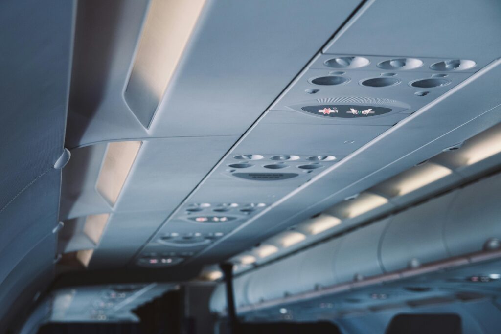 Close-up view of an airplane ceiling panel featuring overhead lights and air vents.