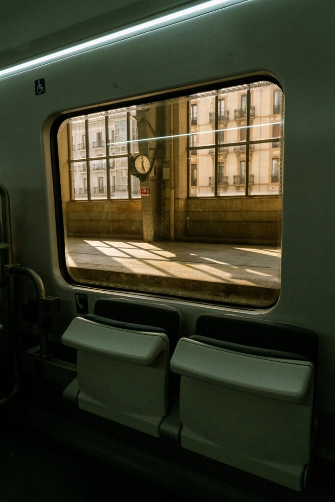 A train window view capturing sunlight at a railway station.