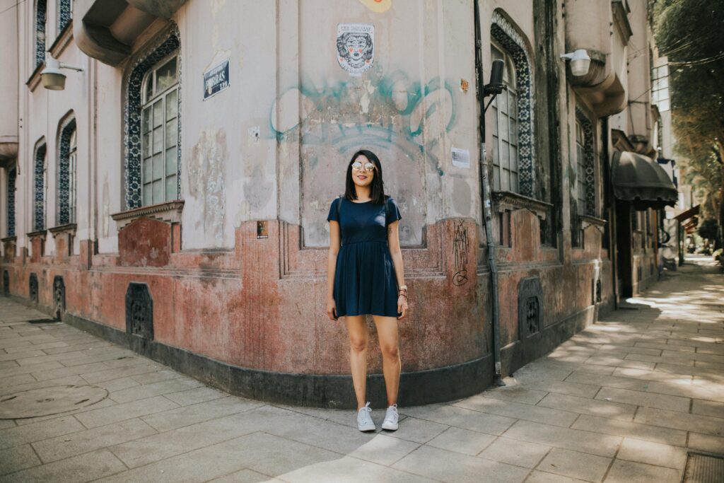 A young woman in casual wear stands by a historic building in Mexico City, exuding urban charm.