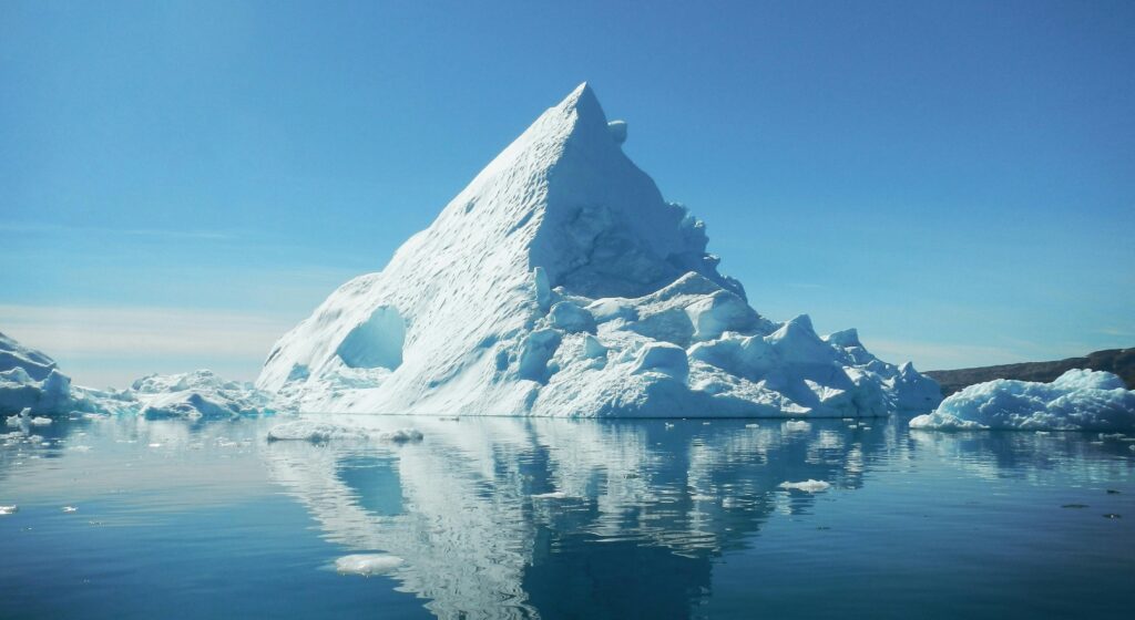 Stunning view of a towering iceberg reflecting in the calm waters of Tiniteqilaaq, Greenland.