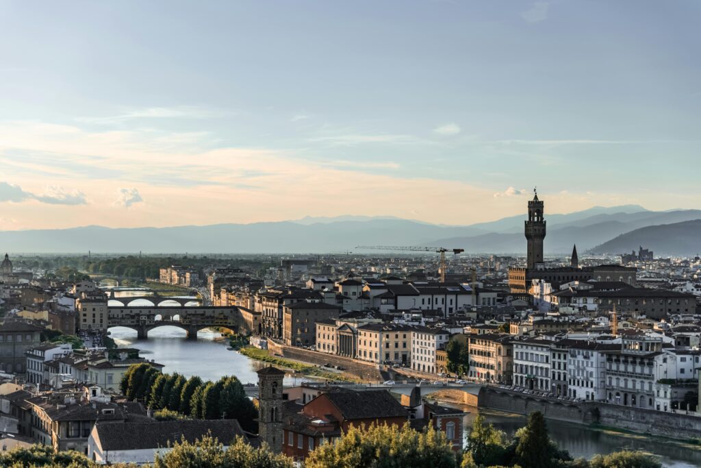 Scenic view of Florence, Italy, featuring iconic landmarks and the Arno River at sunset.